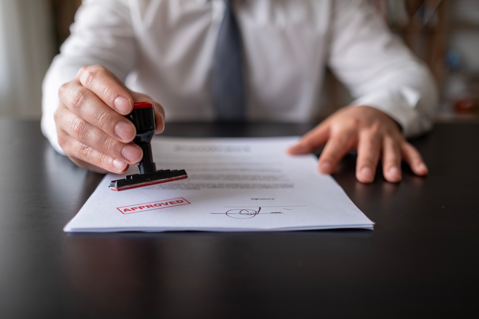 Business Man Stamping With Approved Stamp On Document. Business approve Stamp and certificate concept. Businessman Hands Stamping a document.