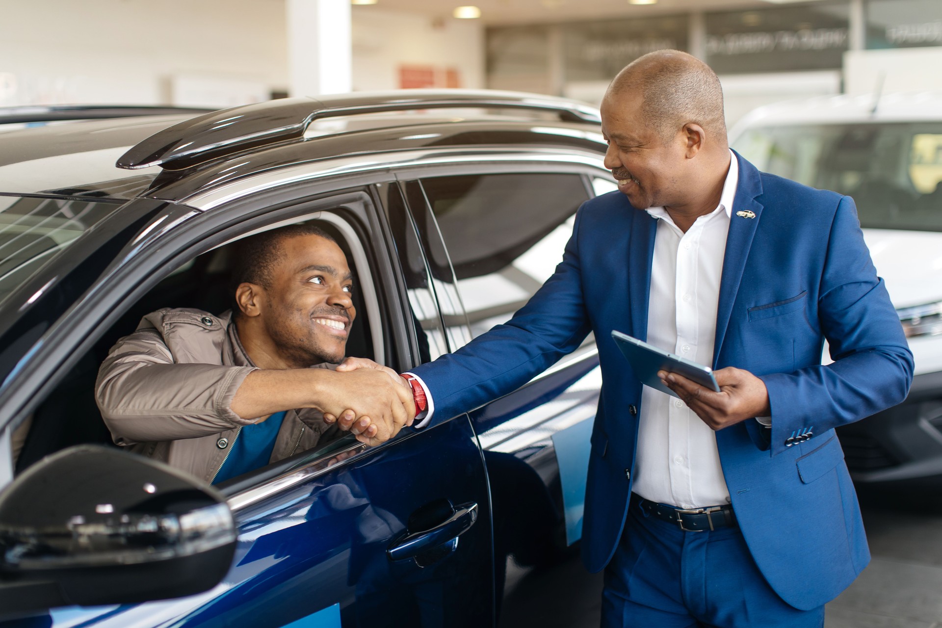 Car Seller Shaking Hands With Buyers After Successful Deal Selling Auto In Dealership Center. Selective Focus
